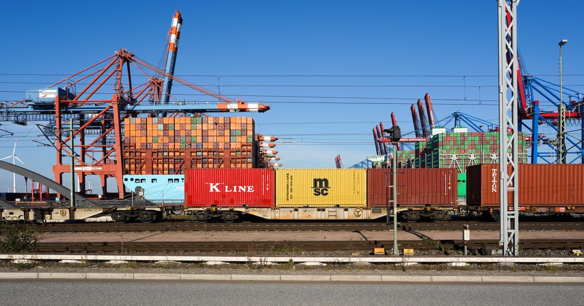 Colorful shipping containers stacked at a port with gantry cranes