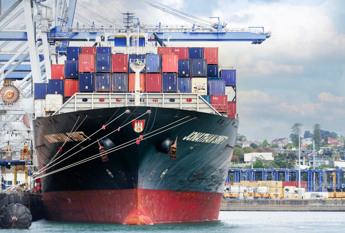 A large cargo ship loaded with shipping containers docked at a commercial port