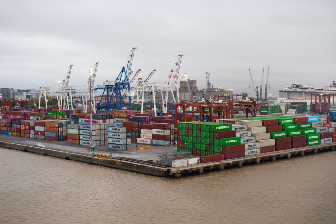 Stacked cargo containers and cranes at a busy commercial shipping port