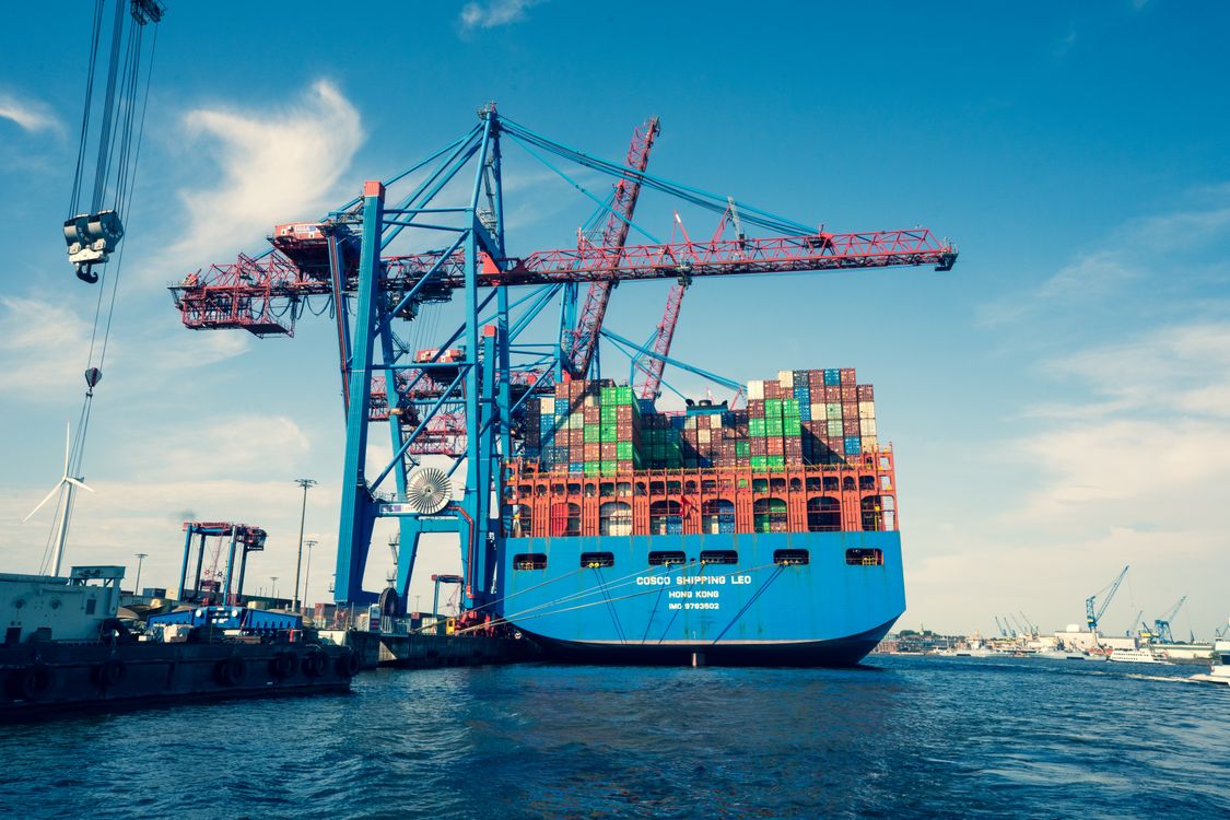 Shipping containers stacked at a busy terminal with cranes