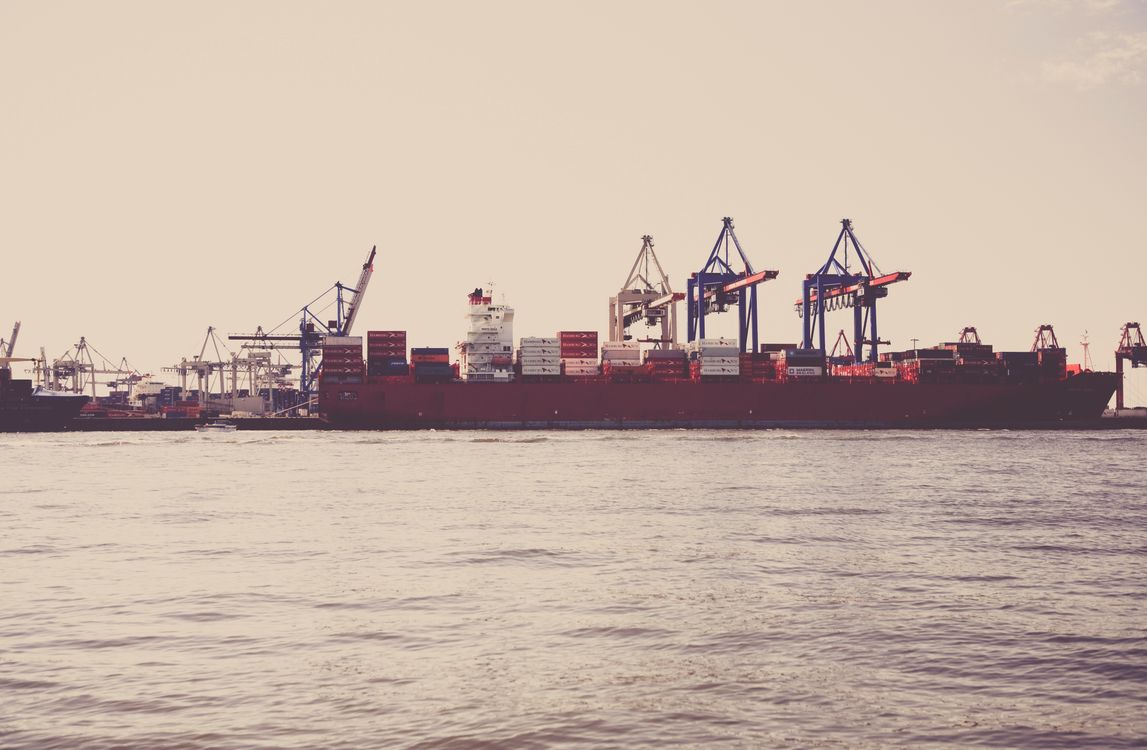 Cargo ship loaded with vehicles and containers docked at an industrial seaport