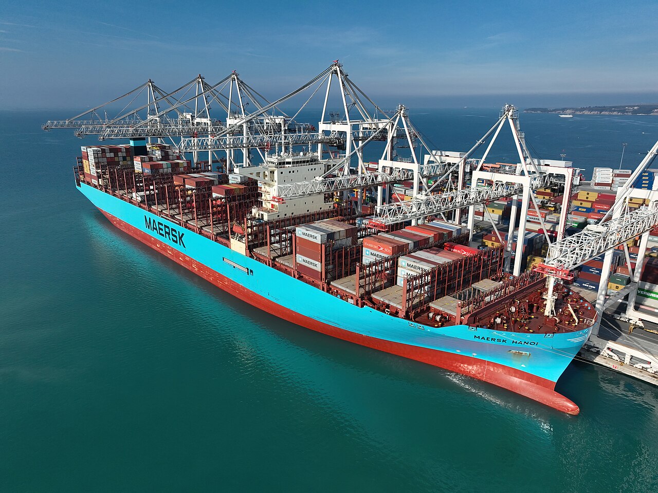Container ship loaded with stacked cargo containers arriving at a deep-sea port terminal